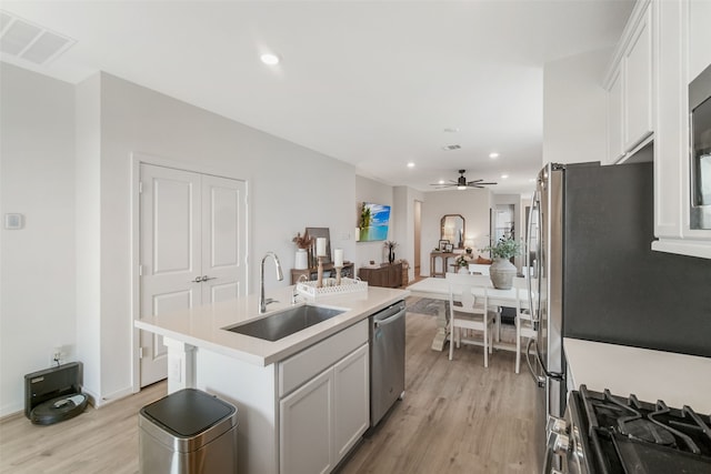 kitchen with a center island with sink, visible vents, appliances with stainless steel finishes, light countertops, and a sink