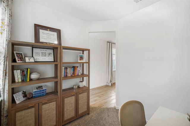 home office with baseboards and light colored carpet