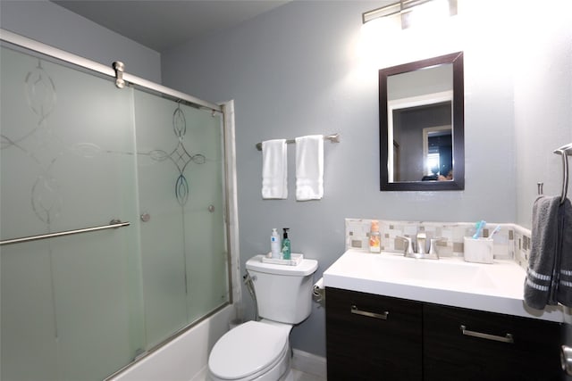 bathroom featuring decorative backsplash, enclosed tub / shower combo, vanity, and toilet