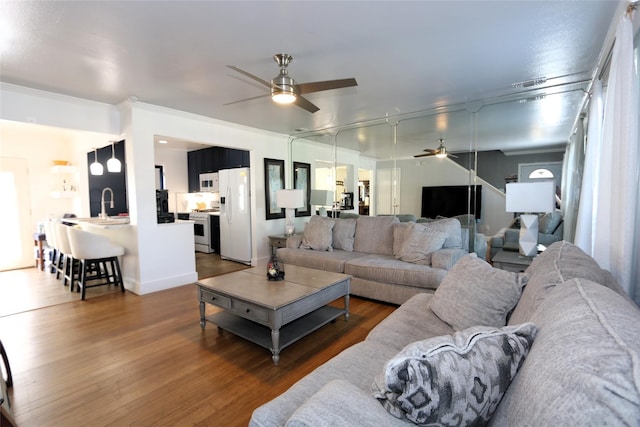 living room with visible vents, a ceiling fan, ornamental molding, wood finished floors, and baseboards