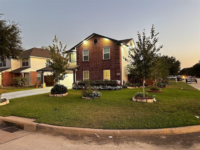 traditional home featuring a garage, concrete driveway, brick siding, and a front yard