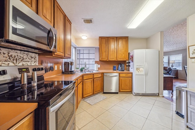 kitchen with visible vents, appliances with stainless steel finishes, brown cabinetry, and a sink