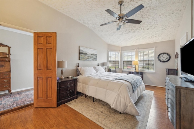 bedroom with lofted ceiling, ceiling fan, a textured ceiling, baseboards, and wood-type flooring