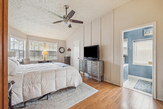 bedroom with baseboards, lofted ceiling, light wood-style flooring, ceiling fan, and a textured ceiling