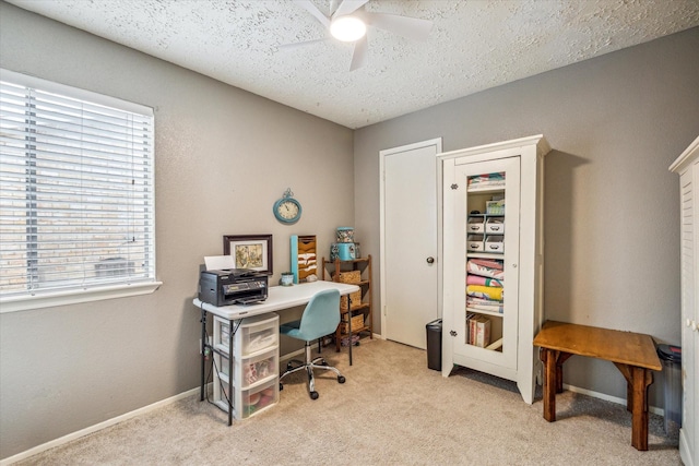 office area with light carpet, a textured ceiling, a ceiling fan, and baseboards