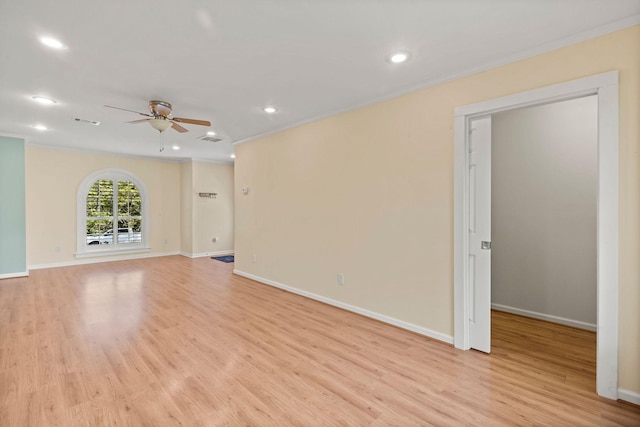 empty room with crown molding, light wood finished floors, and baseboards