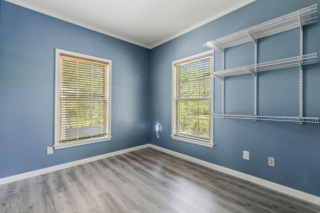 spare room with ornamental molding, wood finished floors, and baseboards