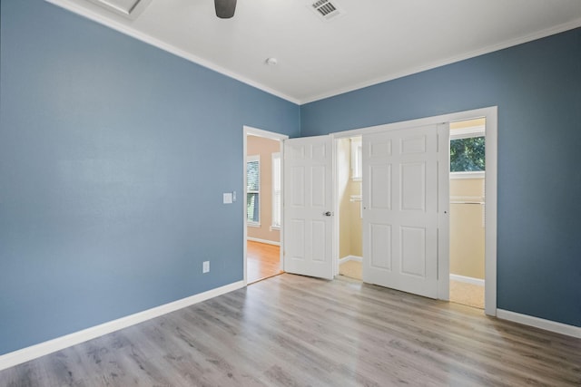 unfurnished bedroom with baseboards, visible vents, a ceiling fan, wood finished floors, and crown molding