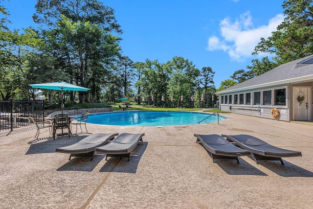 outdoor pool featuring fence and a patio