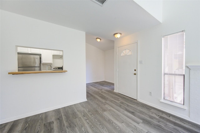 foyer entrance featuring baseboards, visible vents, and wood finished floors