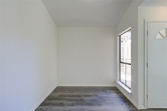 empty room featuring baseboards and dark wood-type flooring