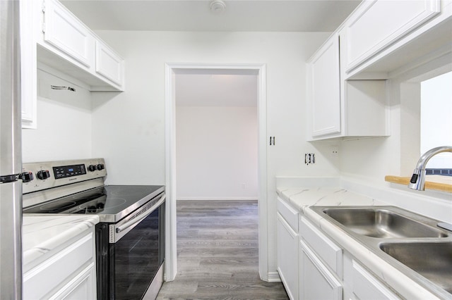 kitchen featuring white cabinetry, stainless steel electric stove, light wood-style flooring, and a sink