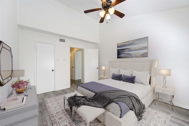 bedroom with ceiling fan, wood finished floors, visible vents, and baseboards