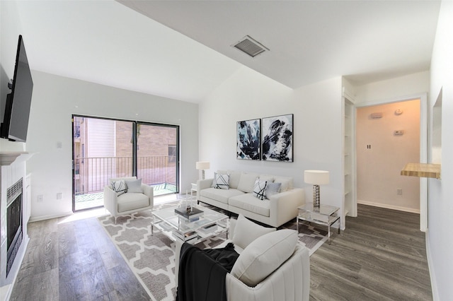 living room with vaulted ceiling, visible vents, a fireplace, and wood finished floors