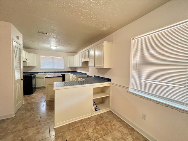 kitchen featuring visible vents, black gas range oven, white cabinets, a textured ceiling, and a peninsula