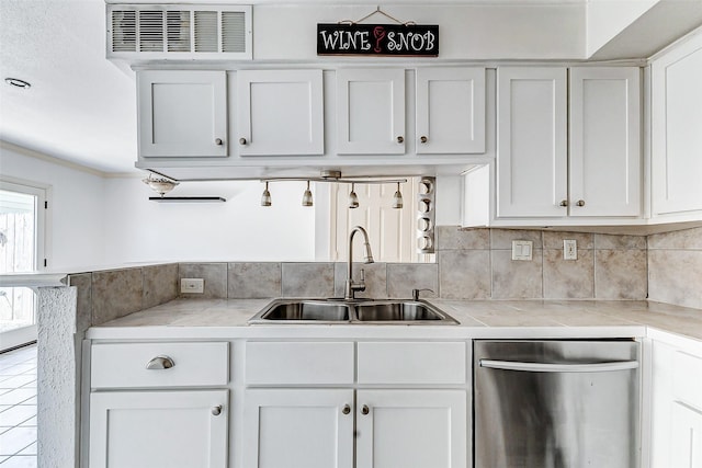 kitchen featuring stainless steel dishwasher, white cabinets, a sink, and light countertops