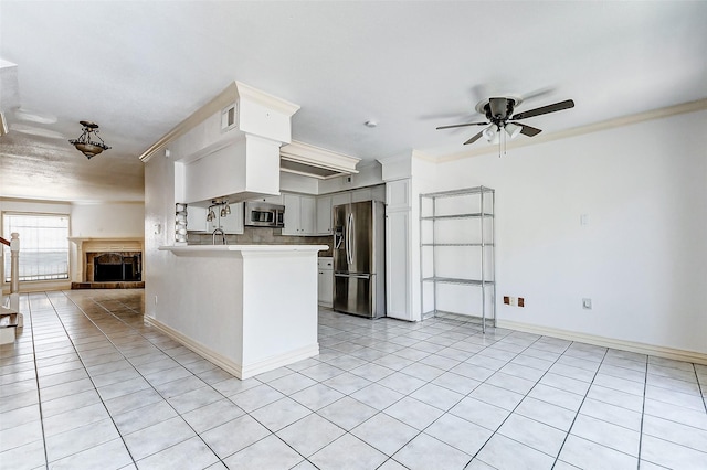 kitchen featuring stainless steel appliances, visible vents, open floor plan, light countertops, and ornamental molding