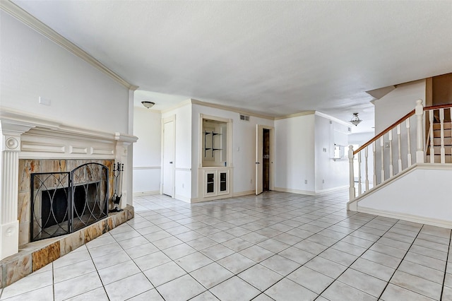 unfurnished living room with light tile patterned floors, visible vents, stairway, a tiled fireplace, and crown molding