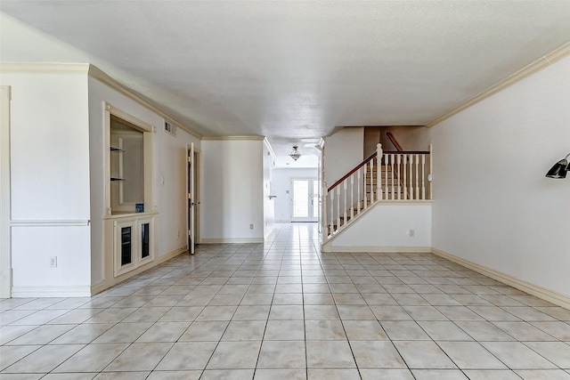 empty room featuring stairway, light tile patterned flooring, visible vents, and crown molding