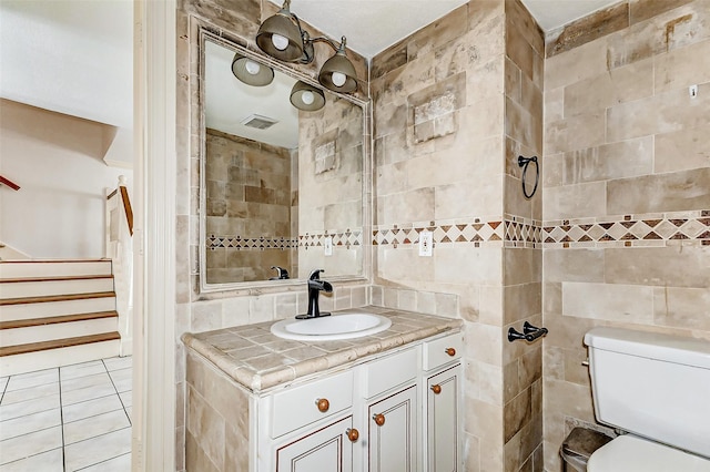 bathroom featuring visible vents, tile walls, toilet, and vanity