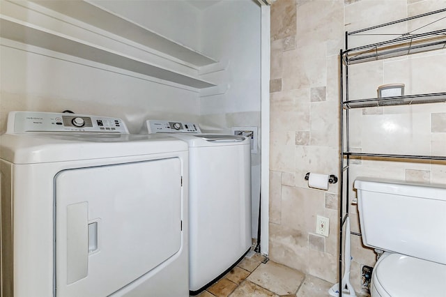 laundry area featuring laundry area, washer and clothes dryer, tile walls, and stone tile floors