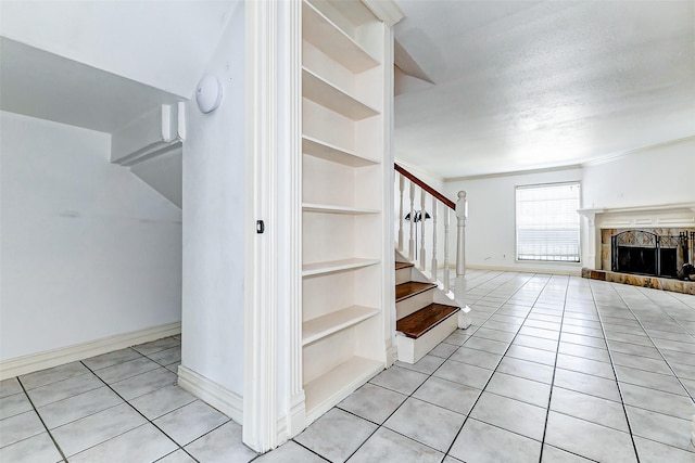 stairs featuring a textured ceiling, a fireplace, baseboards, built in features, and tile patterned floors