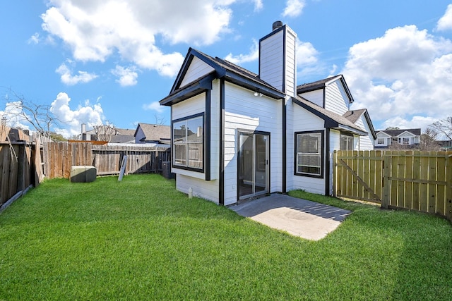 rear view of house with a patio, a fenced backyard, a yard, a gate, and a chimney