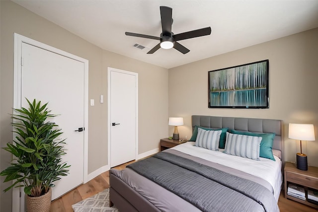 bedroom with visible vents, ceiling fan, baseboards, and wood finished floors