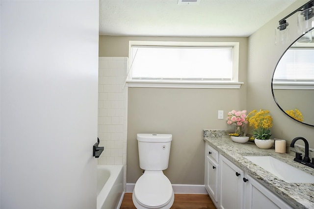 bathroom with toilet, vanity, a wealth of natural light, and baseboards