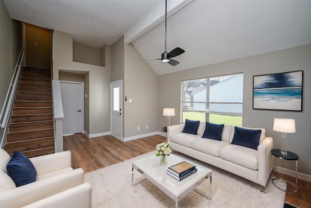 living room featuring stairs, baseboards, beamed ceiling, and wood finished floors