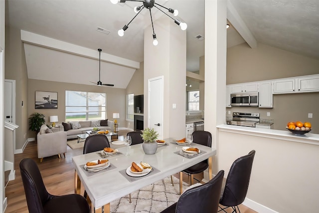 dining room with ceiling fan, light wood-style flooring, beamed ceiling, and visible vents