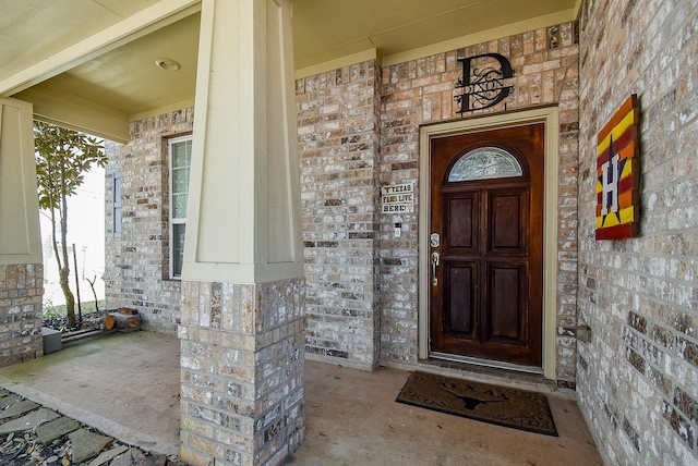 property entrance with covered porch and brick siding