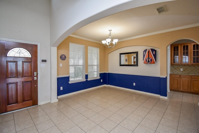 foyer with an inviting chandelier, visible vents, ornamental molding, and light tile patterned flooring