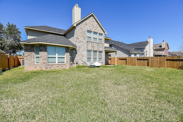 rear view of property with brick siding, a lawn, and a fenced backyard