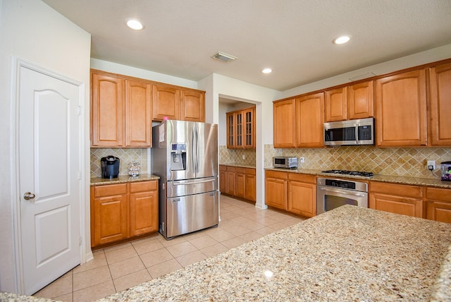 kitchen featuring appliances with stainless steel finishes, light stone countertops, visible vents, and light tile patterned floors