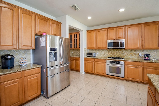 kitchen with visible vents, appliances with stainless steel finishes, decorative backsplash, and light stone counters