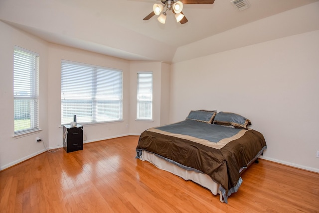 bedroom with light wood-style floors, lofted ceiling, visible vents, and baseboards