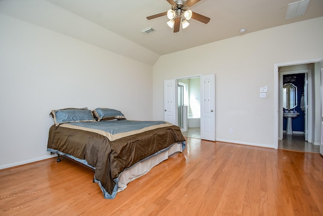 bedroom featuring baseboards, visible vents, vaulted ceiling, and light wood finished floors