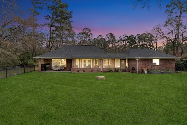 view of front of home featuring brick siding, a front yard, a fenced backyard, and a shingled roof