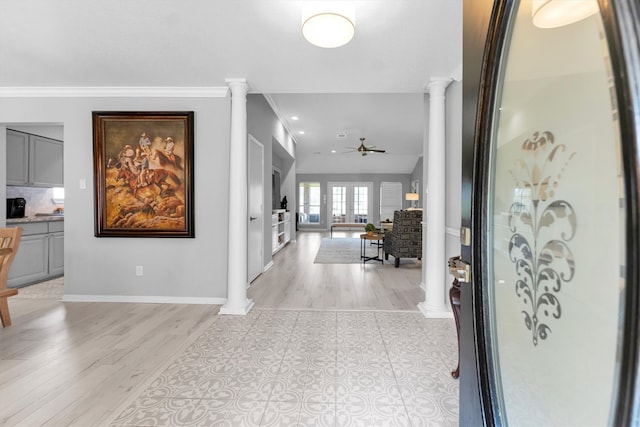 foyer featuring ceiling fan, light wood-style flooring, baseboards, ornamental molding, and decorative columns