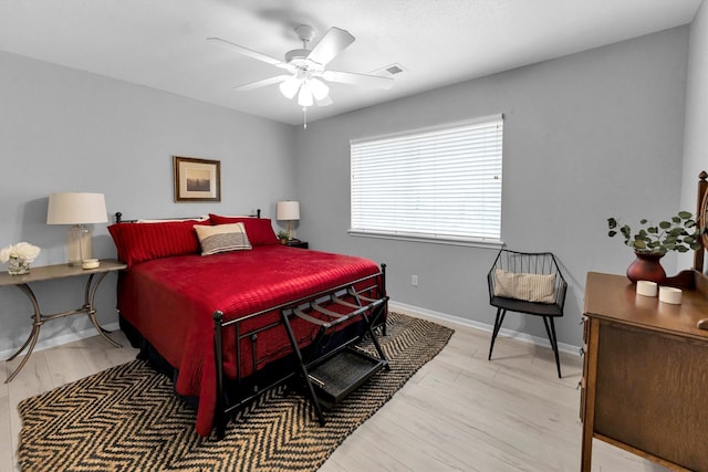 bedroom featuring a ceiling fan, wood finished floors, visible vents, and baseboards