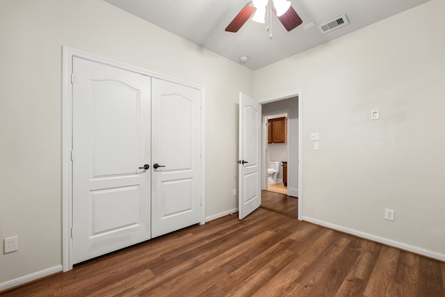 unfurnished bedroom with baseboards, visible vents, dark wood finished floors, ceiling fan, and a closet