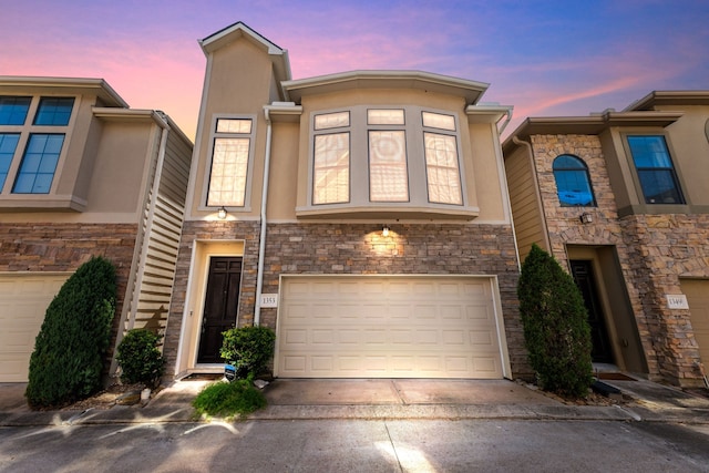 townhome / multi-family property featuring a garage, concrete driveway, stone siding, and stucco siding