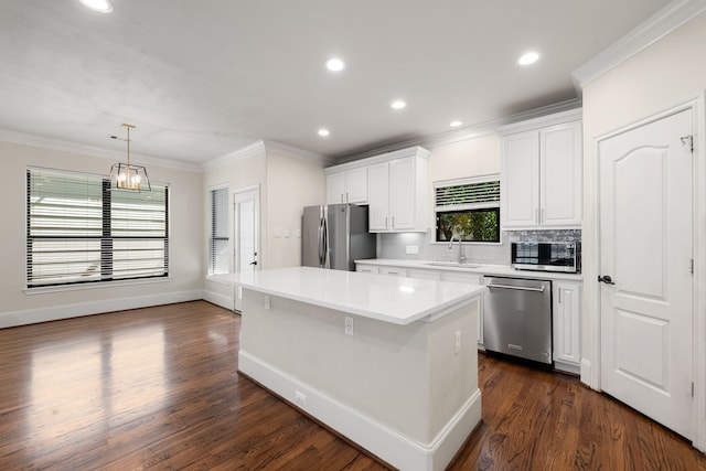 kitchen with a sink, white cabinets, light countertops, ornamental molding, and appliances with stainless steel finishes