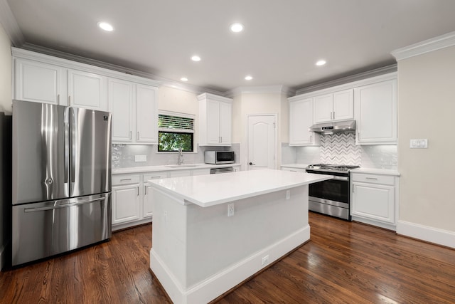 kitchen with a center island, stainless steel appliances, under cabinet range hood, white cabinetry, and a sink