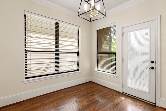 interior space featuring baseboards, ornamental molding, a chandelier, and wood finished floors