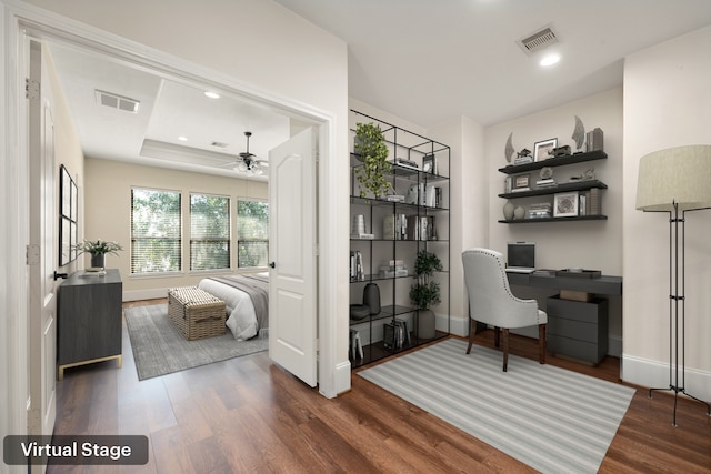 office space featuring a tray ceiling, visible vents, recessed lighting, and wood finished floors