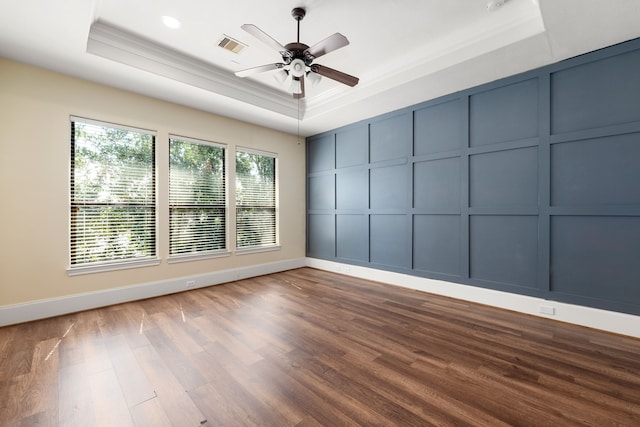 spare room featuring ornamental molding, a tray ceiling, a decorative wall, and wood finished floors