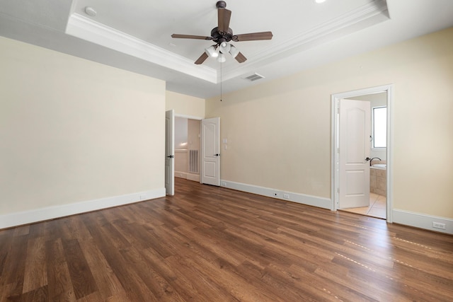 unfurnished bedroom featuring a raised ceiling, visible vents, crown molding, and wood finished floors