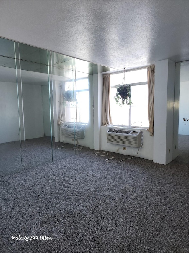 unfurnished bedroom with carpet flooring, a textured ceiling, and a wall mounted AC